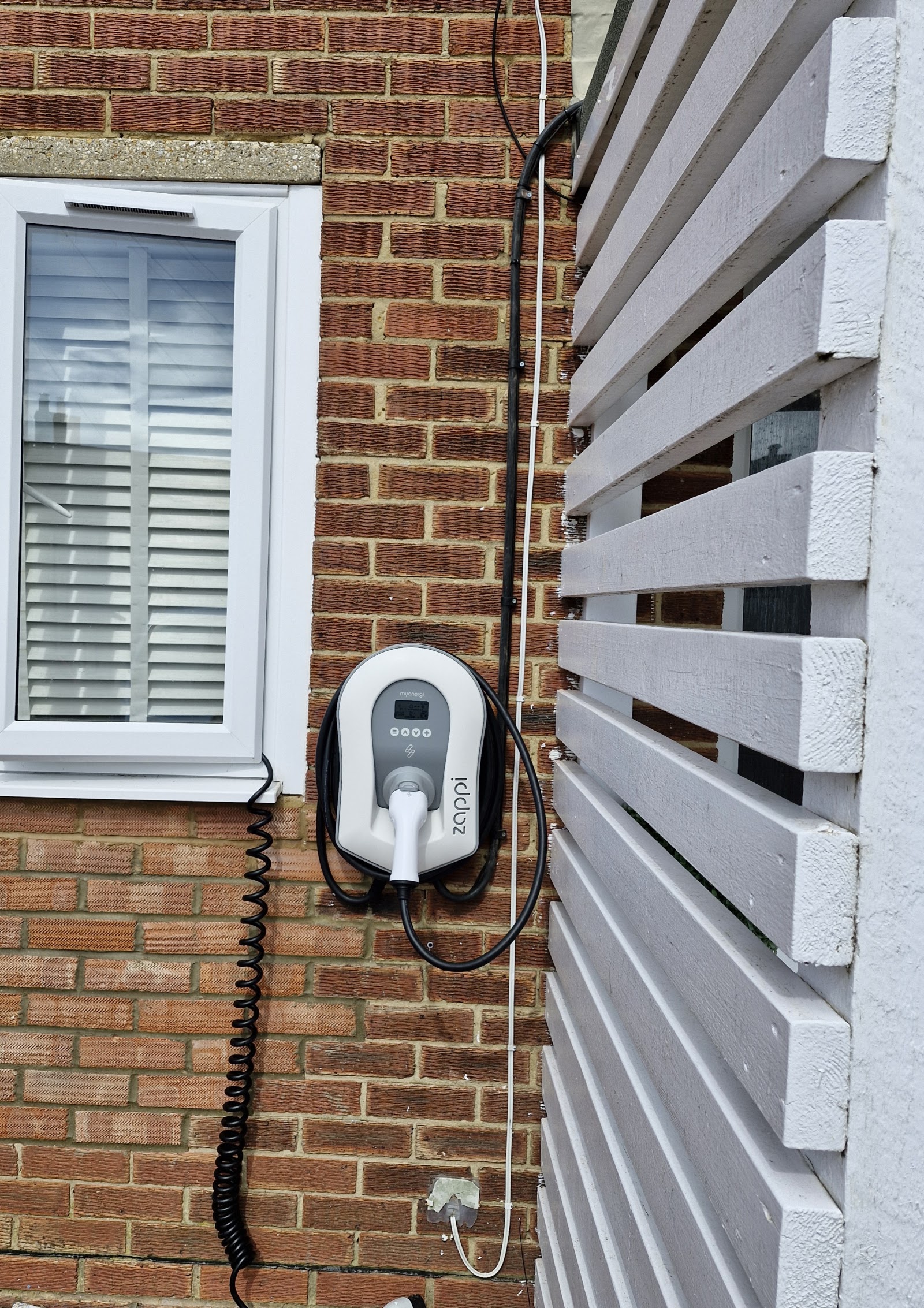 Home car charge point fitted neatly beside a window on a brick wall